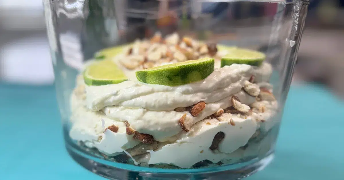 A glass dish filled with a creamy dessert, garnished with fresh lime slices on top.