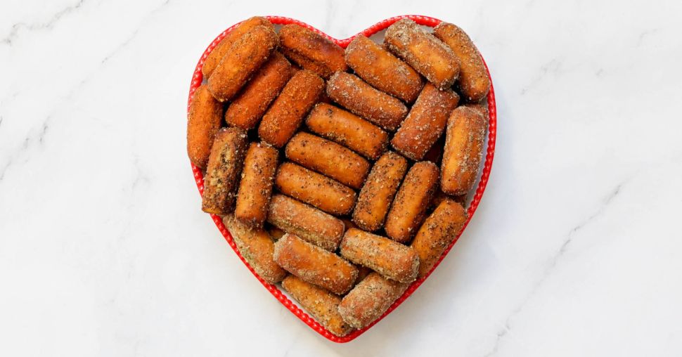 Red heart bowl with a variety of OMG! Pretzel flavors on a marble countertop