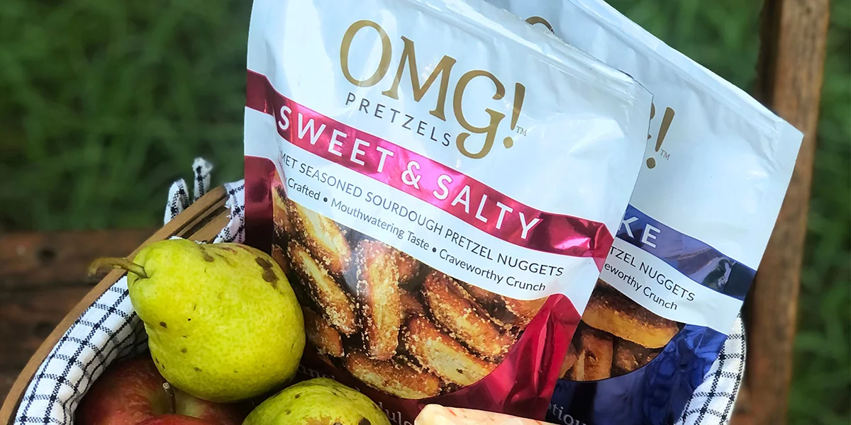A variety of omg's sweet and savory snacks displayed on a wooden table, showcasing colorful packaging and diverse flavors.