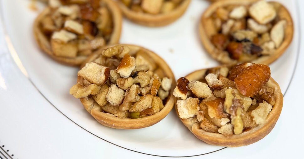 A plate featuring small pastry shells filled with a variety of nuts, elegantly arranged for presentation.