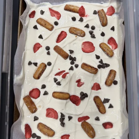 A sheet of white paper featuring scattered chocolate chips and fresh strawberries arranged artistically.