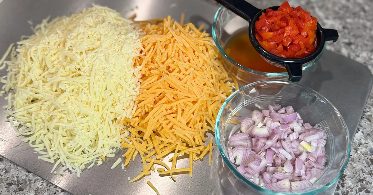 A metal tray filled with assorted cheese, sliced onions, and colorful peppers arranged neatly.