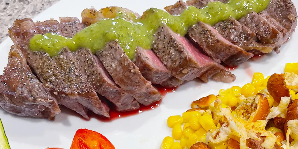 A plate featuring Italian sushi with steak, corn, and tomatoes arranged artfully.