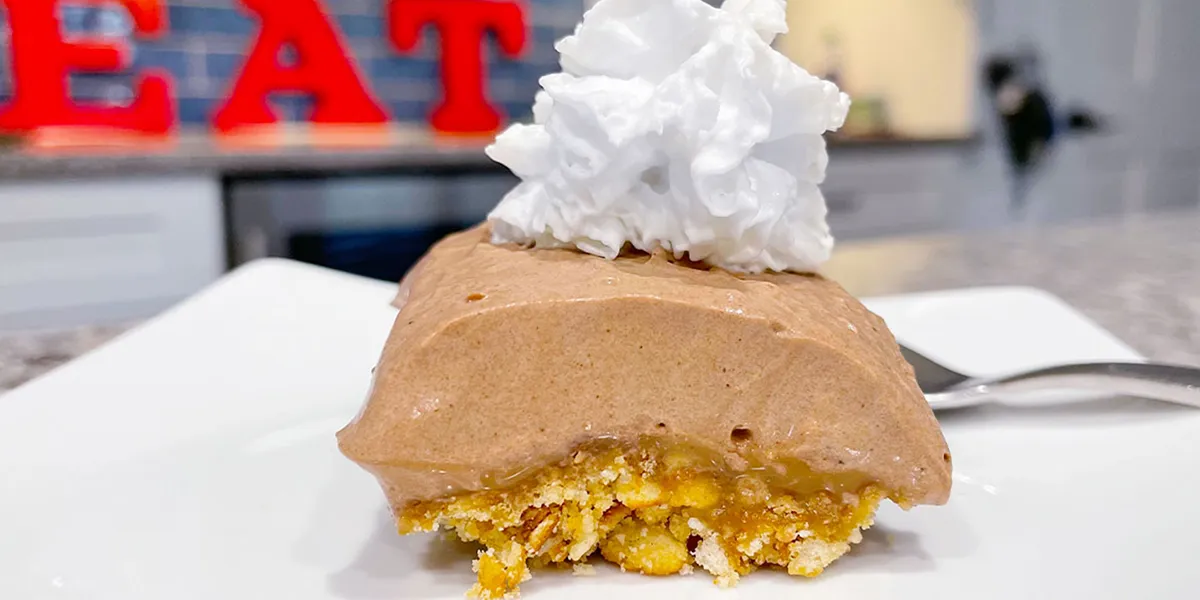 A slice of ice cream cake topped with a generous swirl of whipped cream.
