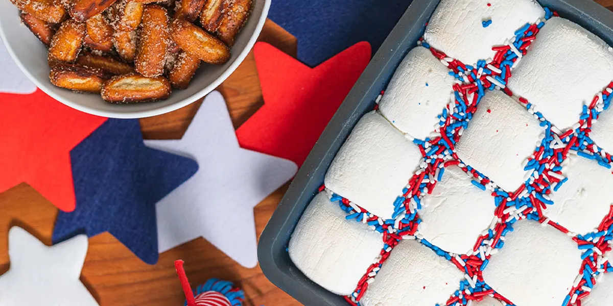 A tray filled with fluffy marshmallows alongside a bowl of red, white, and blue festive treats.