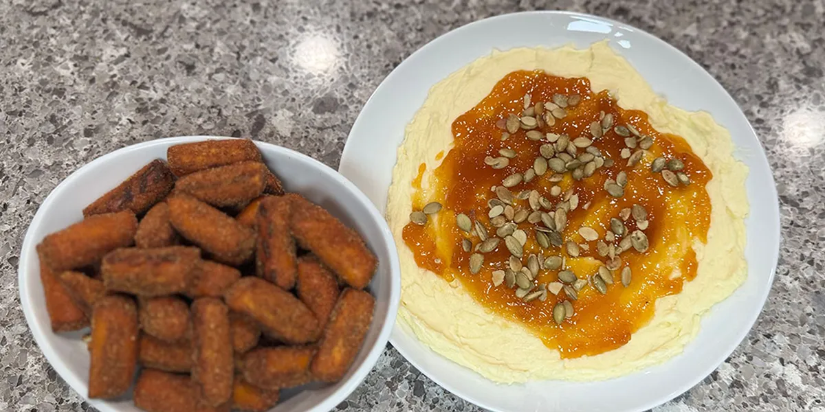 A plate featuring a bowl of hummus accompanied by an assortment of fried foods.