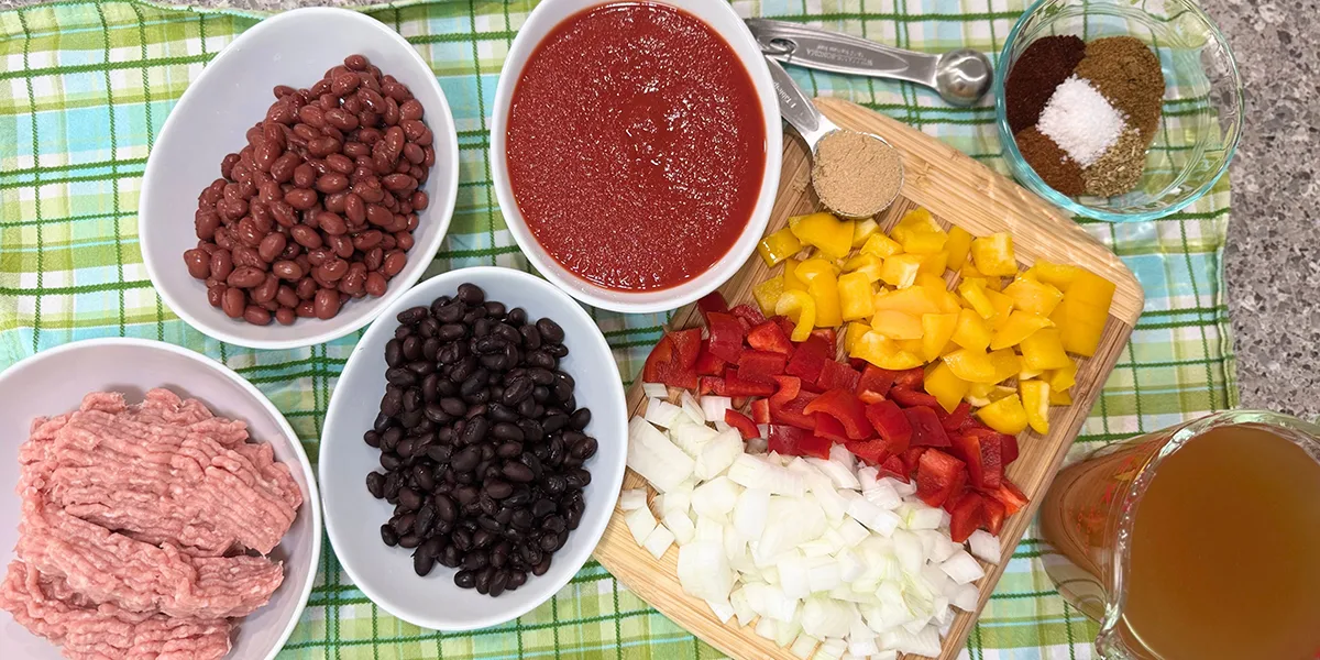 A variety of ingredients for Mexican meatloaf, including ground beef, spices, and vegetables arranged on a countertop.
