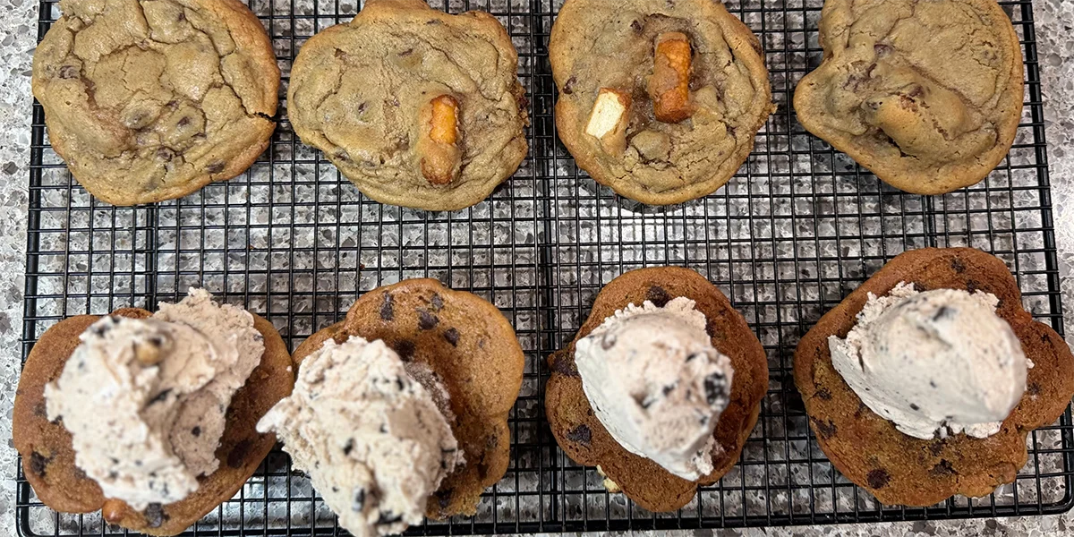Cookies cooling on a wire rack. The top row has cookie pieces with pretzels, while the bottom row has scoops of ice cream on cookies.