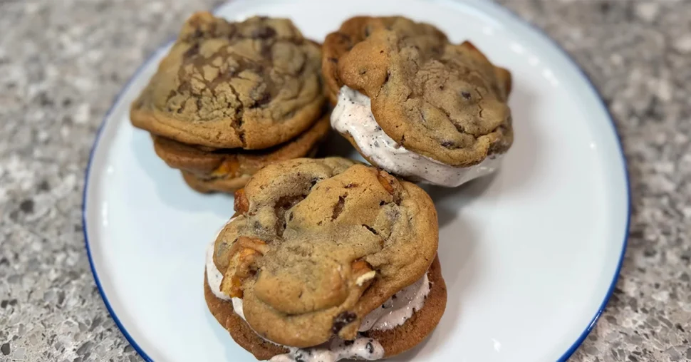 Three cookies topped with ice cream arranged on a white plate, creating a delicious dessert presentation.