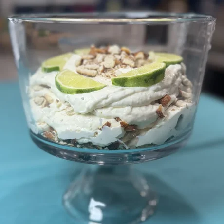 A glass dish filled with a creamy dessert, garnished with fresh lime slices on top.