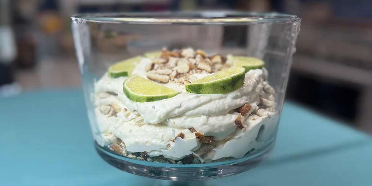 A glass dish filled with a creamy dessert, garnished with fresh lime slices on top.