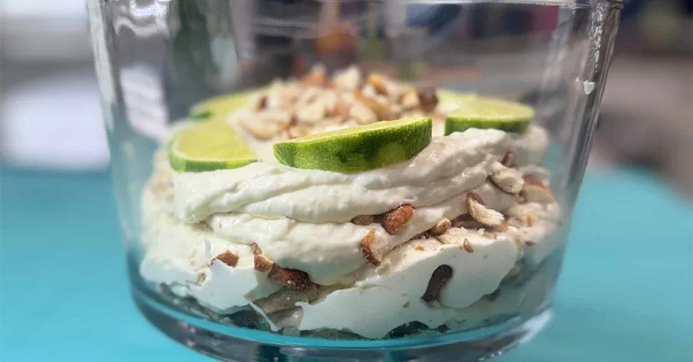 A glass dish filled with a creamy dessert, garnished with fresh lime slices on top.